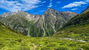 Live from St. Leonhard im Pitztal Green mountain trail under blue sky with snow-capped peaks