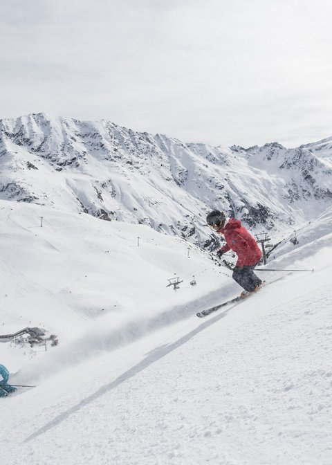 Nicht irgendein Pitztal-Resort: Alpine Resort Sportalm! Zwei Skifahrer fahren einen schneebedeckten Hang in den Bergen hinunter