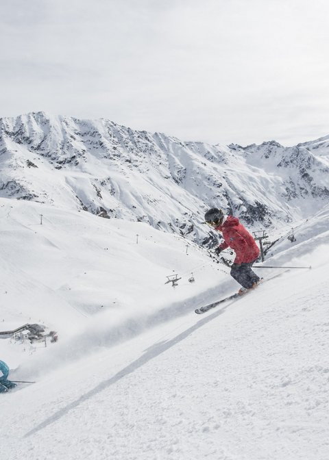 Nicht irgendein Pitztal-Resort: Alpine Resort Sportalm! Zwei Skifahrer fahren einen schneebedeckten Hang in den Bergen hinunter