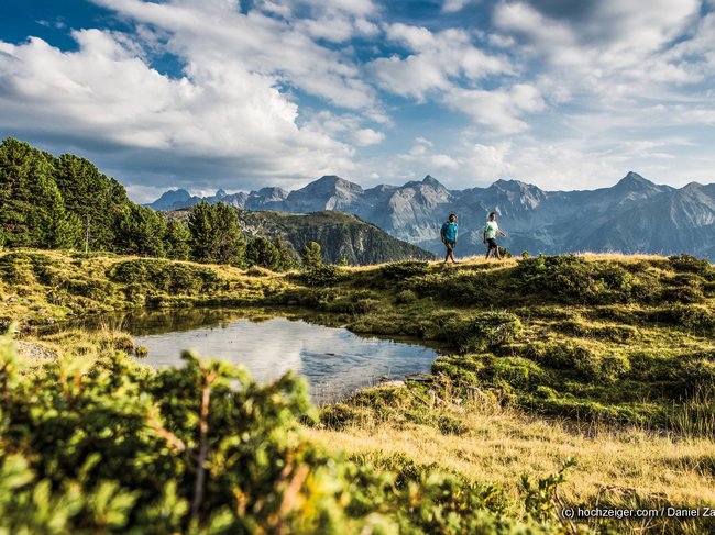 Nicht irgendein Pitztal-Resort: Alpine Resort Sportalm! Zwei Wanderer auf einem Bergweg mit See und Alpen im Hintergrund