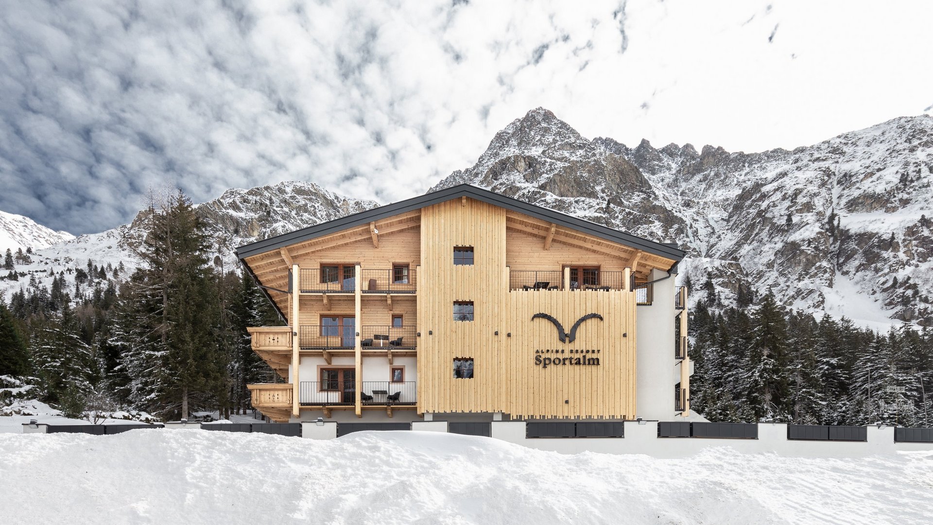 Nicht irgendein Pitztal-Resort: Alpine Resort Sportalm! Alpenresort Sportalm vor verschneiten Bergen und Wald