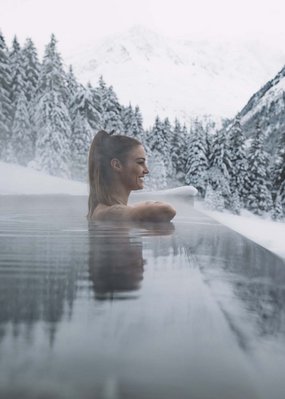 Nicht irgendein Pitztal-Resort: Alpine Resort Sportalm! Frau entspannt in beheiztem Pool umgeben von verschneiten Bergen und Bäumen
