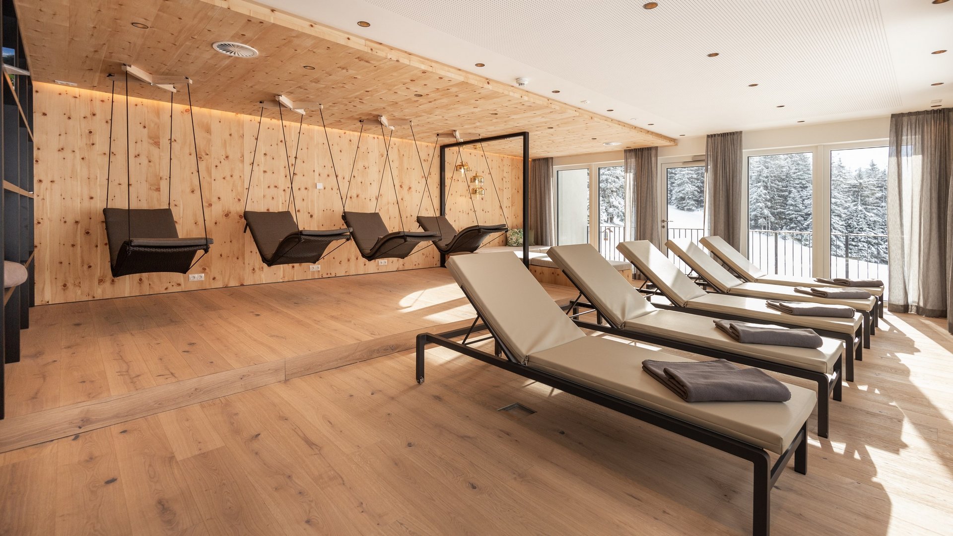 Live from St. Leonhard im Pitztal Modern relaxation room with hanging chairs and loungers by windows showing snow outside