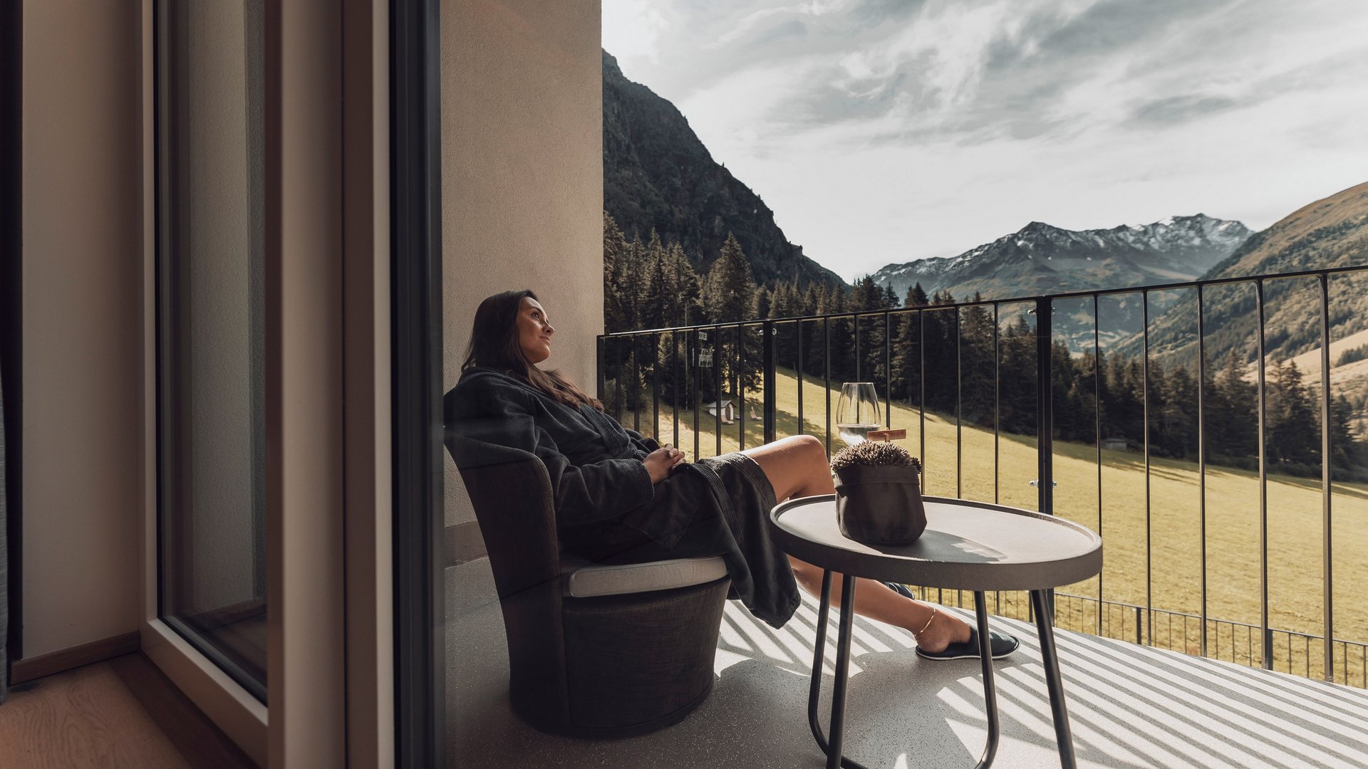 Live from St. Leonhard im Pitztal Woman relaxing on balcony with mountain view wearing a bathrobe