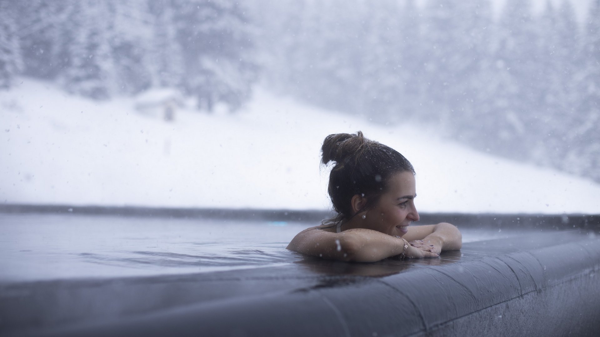 Live from St. Leonhard im Pitztal Woman relaxing in heated outdoor pool while snow is falling