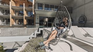 Nicht irgendein Pitztal-Resort: Alpine Resort Sportalm! Frau entspannt im Schaukelstuhl auf Hotelterrasse bei Sonnenschein